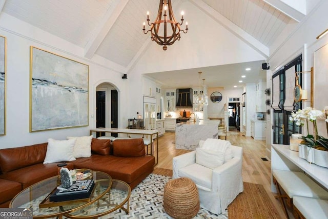 living room with high vaulted ceiling, an inviting chandelier, beam ceiling, and light hardwood / wood-style flooring