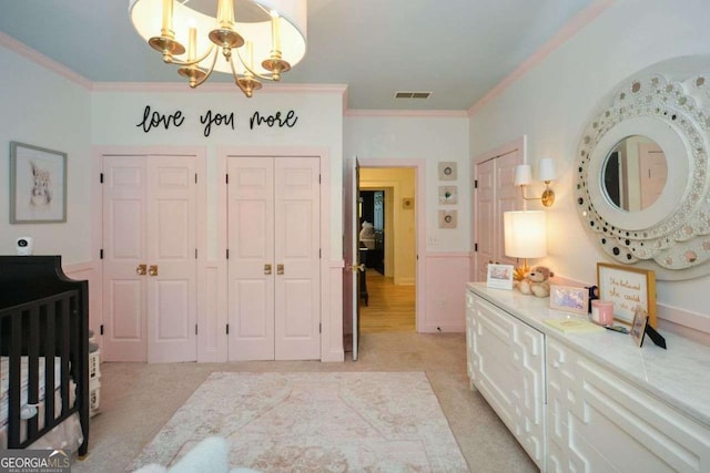 bedroom with crown molding, light carpet, two closets, and a notable chandelier