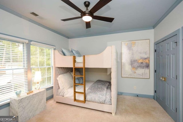 carpeted bedroom with crown molding, ceiling fan, and a closet