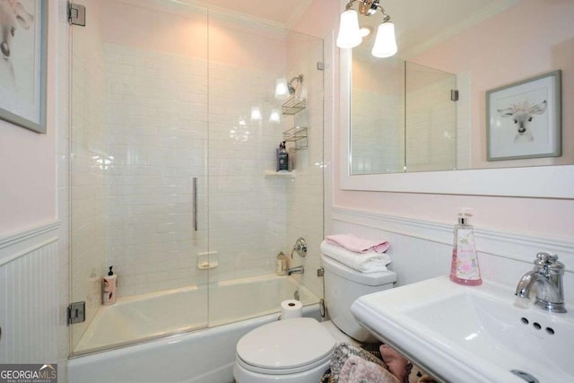 full bathroom featuring sink, crown molding, enclosed tub / shower combo, and toilet