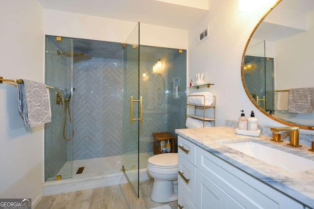 bathroom featuring vanity, toilet, a shower with shower door, and wood-type flooring