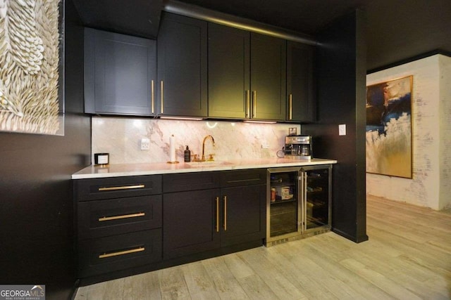 kitchen featuring wine cooler, sink, decorative backsplash, and light hardwood / wood-style floors