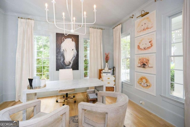 sitting room with an inviting chandelier, ornamental molding, a wealth of natural light, and light hardwood / wood-style floors