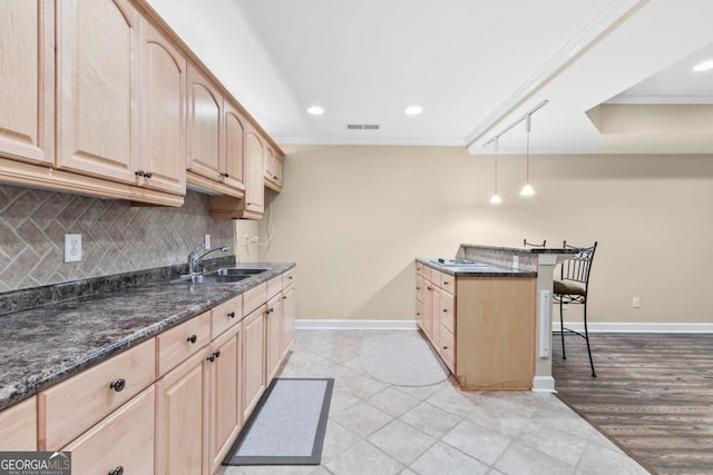 kitchen featuring a breakfast bar, pendant lighting, dark stone countertops, and sink