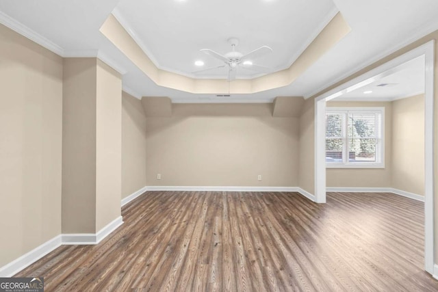 spare room featuring a raised ceiling, ceiling fan, hardwood / wood-style floors, and ornamental molding