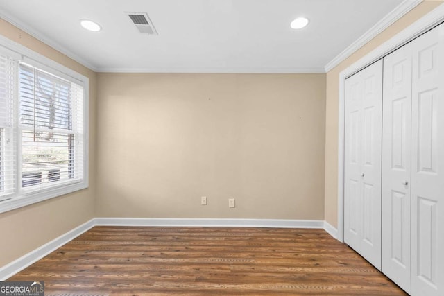 unfurnished bedroom with a closet, dark hardwood / wood-style flooring, and ornamental molding