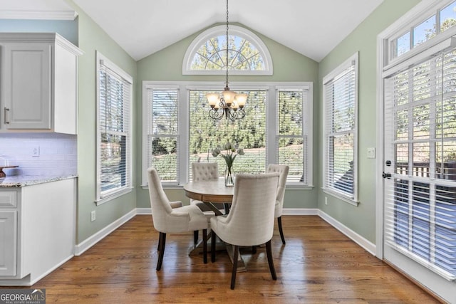 dining area featuring lofted ceiling, dark wood-type flooring, a wealth of natural light, and a chandelier