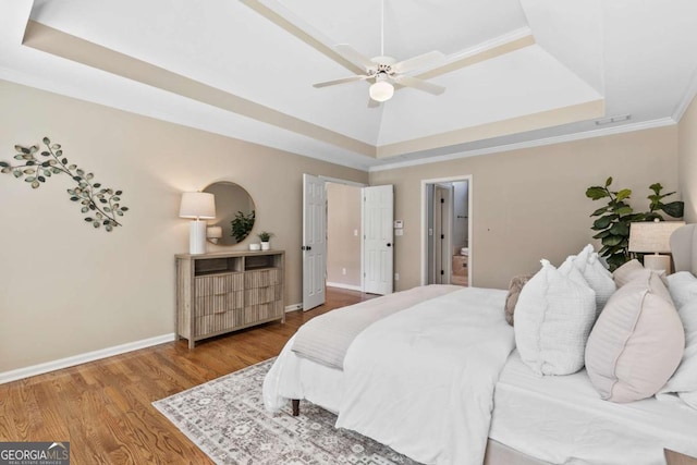 bedroom featuring a tray ceiling, ceiling fan, crown molding, and hardwood / wood-style floors