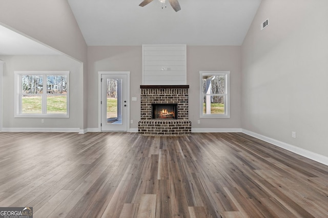 unfurnished living room with dark wood finished floors, a fireplace, visible vents, a ceiling fan, and high vaulted ceiling