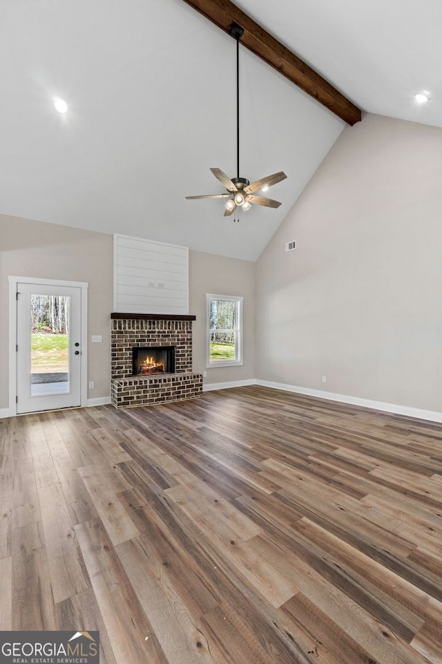 unfurnished living room with high vaulted ceiling, a fireplace, wood finished floors, baseboards, and beam ceiling