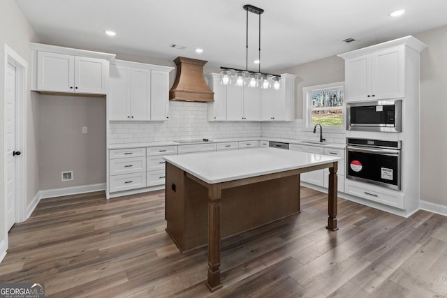 kitchen featuring stainless steel appliances, premium range hood, backsplash, and white cabinets