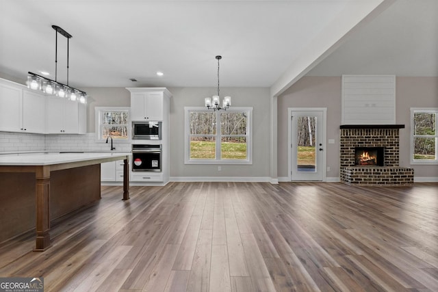 kitchen with tasteful backsplash, appliances with stainless steel finishes, open floor plan, light countertops, and a sink