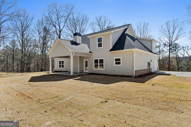 back of property with a patio area, a shingled roof, and a chimney