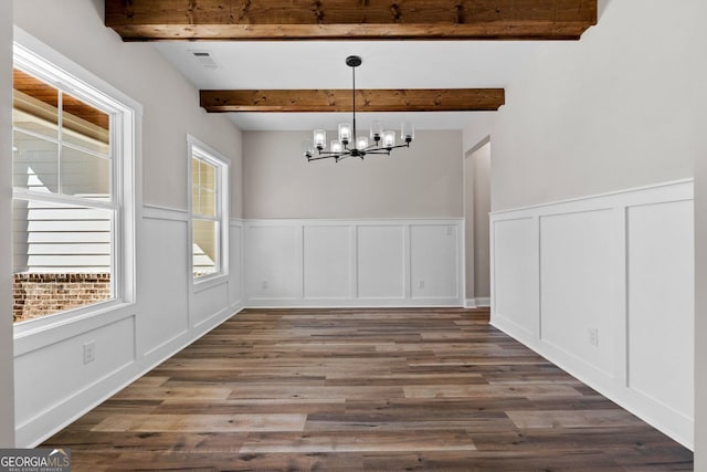 unfurnished dining area featuring a decorative wall, wood finished floors, beam ceiling, and an inviting chandelier