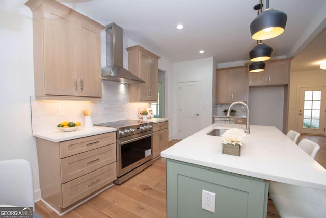 kitchen with electric range, wall chimney exhaust hood, sink, and tasteful backsplash