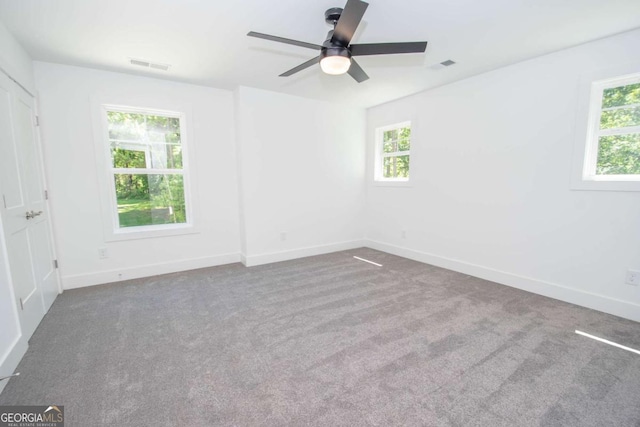 empty room featuring ceiling fan, carpet floors, and a healthy amount of sunlight