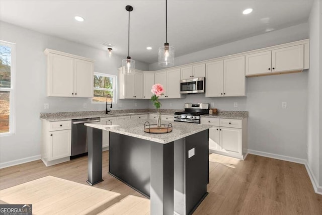 kitchen with appliances with stainless steel finishes, white cabinetry, and a kitchen island