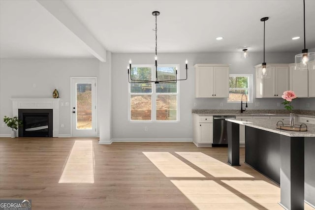 kitchen featuring white cabinetry, stainless steel dishwasher, decorative light fixtures, and light wood-type flooring