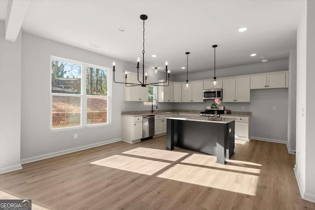 kitchen with a center island, hanging light fixtures, light hardwood / wood-style flooring, white cabinets, and appliances with stainless steel finishes