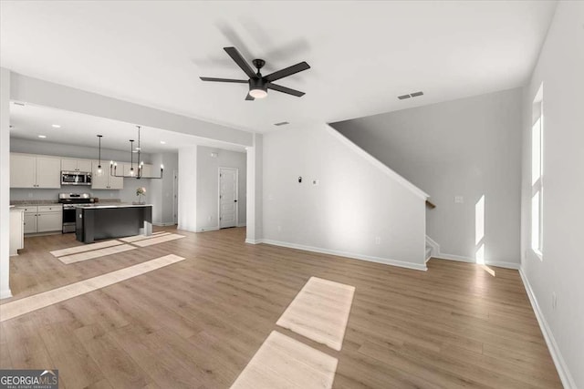 unfurnished living room with ceiling fan and light hardwood / wood-style floors