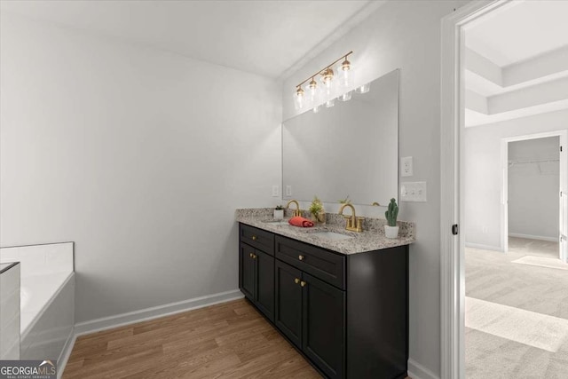 bathroom with a washtub, vanity, and hardwood / wood-style floors