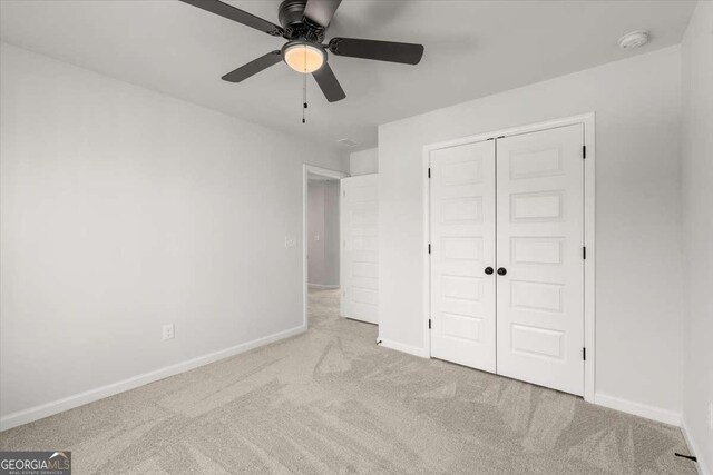 unfurnished bedroom with ceiling fan, a closet, and light colored carpet