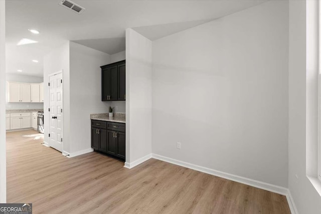 kitchen with white cabinets, stove, and light hardwood / wood-style floors