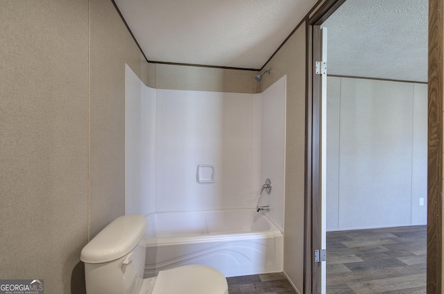 bathroom featuring bathtub / shower combination, a textured ceiling, hardwood / wood-style flooring, and toilet