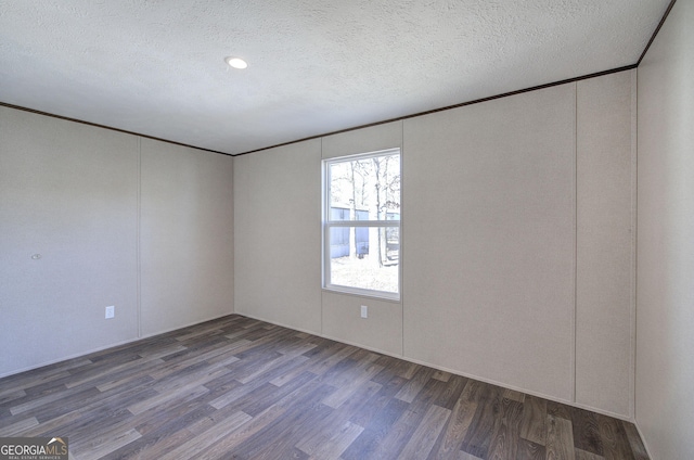 spare room featuring a textured ceiling and dark hardwood / wood-style floors