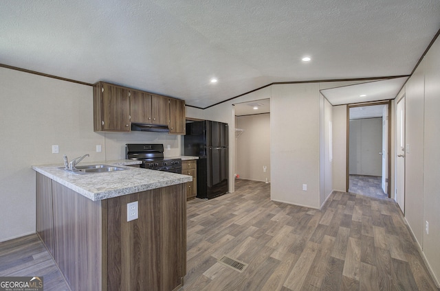 kitchen featuring hardwood / wood-style floors, black appliances, sink, vaulted ceiling, and a textured ceiling