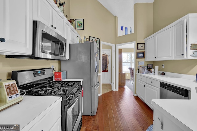 kitchen with white cabinets, a high ceiling, stainless steel appliances, and dark wood-type flooring