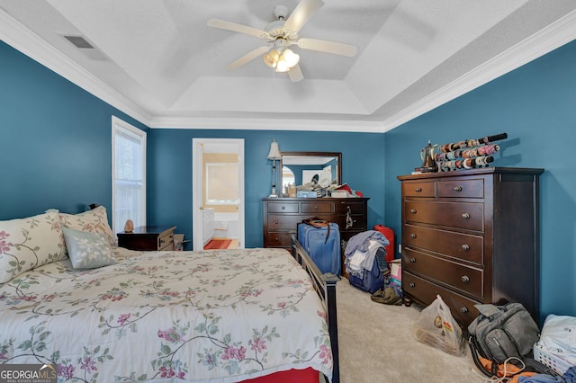 carpeted bedroom featuring ensuite bathroom, a raised ceiling, ceiling fan, and crown molding