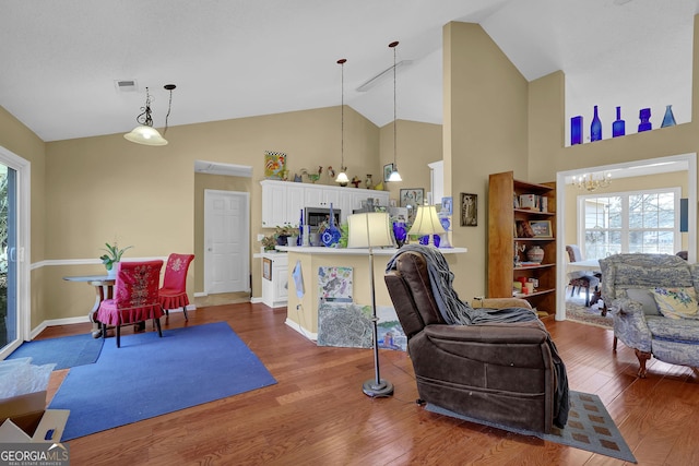 living room with high vaulted ceiling, wood-type flooring, and a notable chandelier