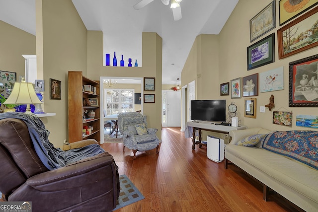 living room featuring hardwood / wood-style floors, ceiling fan with notable chandelier, and high vaulted ceiling