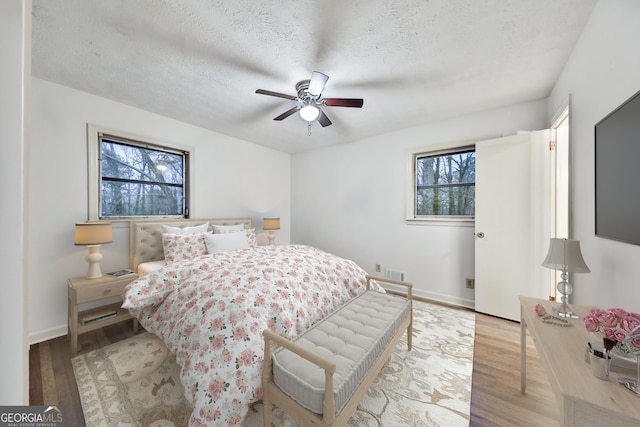 bedroom with multiple windows, ceiling fan, and light wood-type flooring