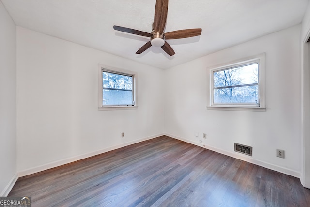 empty room featuring ceiling fan, a healthy amount of sunlight, and dark hardwood / wood-style flooring