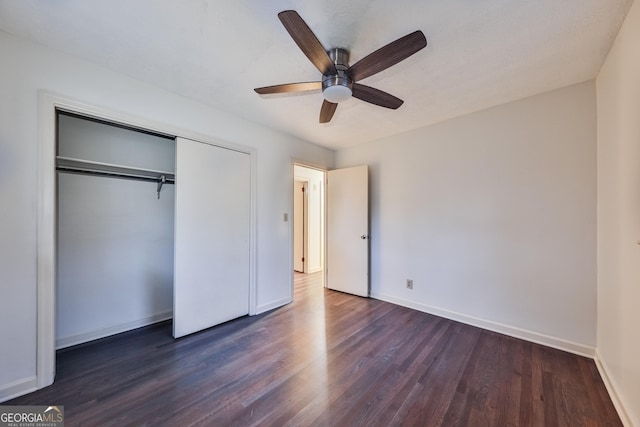 unfurnished bedroom with dark hardwood / wood-style flooring, a closet, and ceiling fan