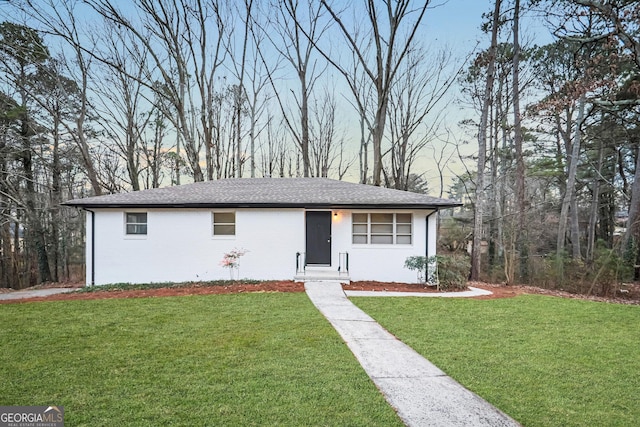 single story home with brick siding, a shingled roof, and a front yard