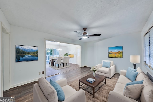 living room featuring a textured ceiling, wood finished floors, and ceiling fan with notable chandelier