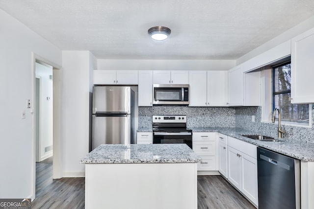 kitchen with appliances with stainless steel finishes, white cabinetry, and a kitchen island