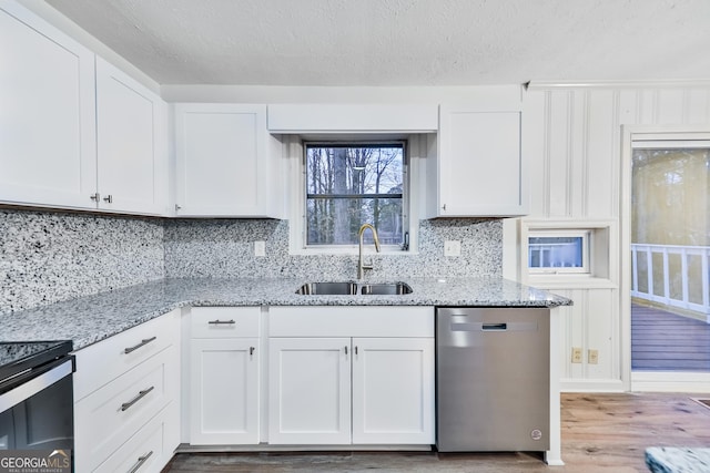 kitchen with dishwasher, white cabinetry, and sink