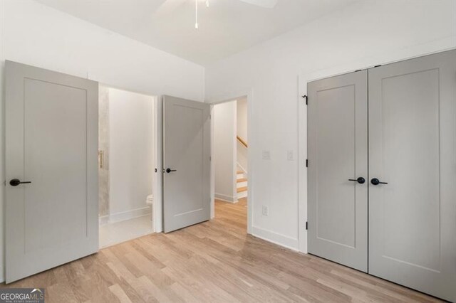 unfurnished bedroom featuring light wood-type flooring, a closet, ceiling fan, and connected bathroom