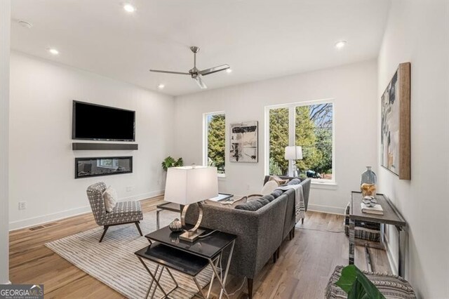 living room with ceiling fan and light hardwood / wood-style flooring