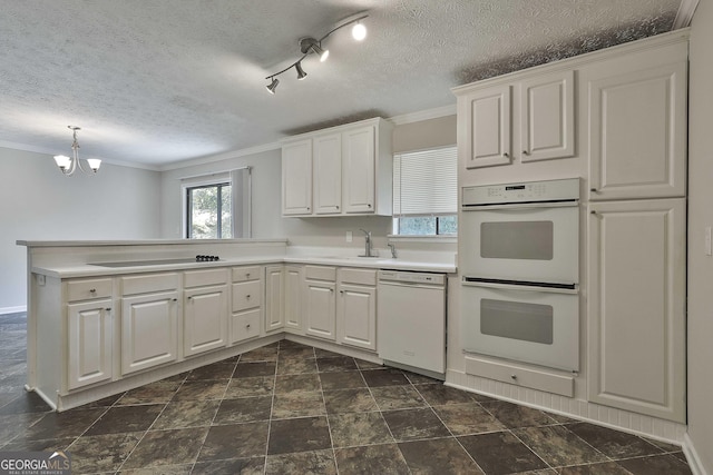 kitchen with a textured ceiling, white cabinetry, white appliances, and kitchen peninsula