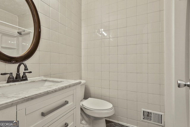 bathroom with vanity, toilet, and tile walls