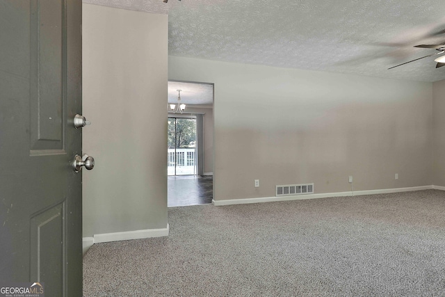 empty room with ceiling fan, a textured ceiling, and dark colored carpet