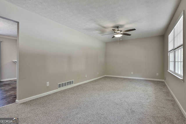 unfurnished room with a textured ceiling, dark carpet, and ceiling fan