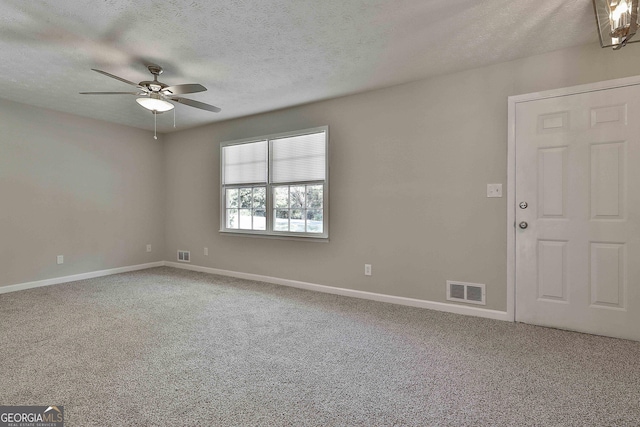 carpeted empty room featuring ceiling fan and a textured ceiling