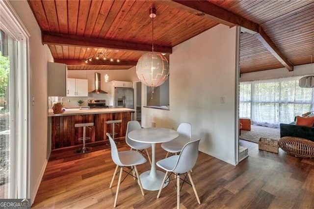 dining space featuring beamed ceiling, hardwood / wood-style floors, and wooden ceiling