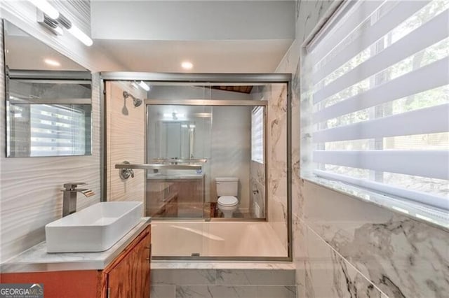 bathroom featuring vanity, a shower with shower door, tile walls, and toilet